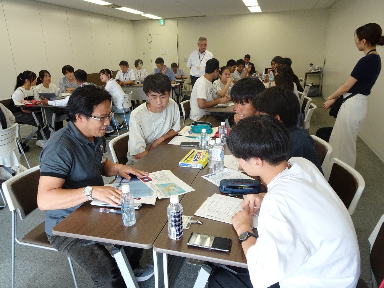 JDS生とのワークショップを見守る平川特命審議役と津田職員